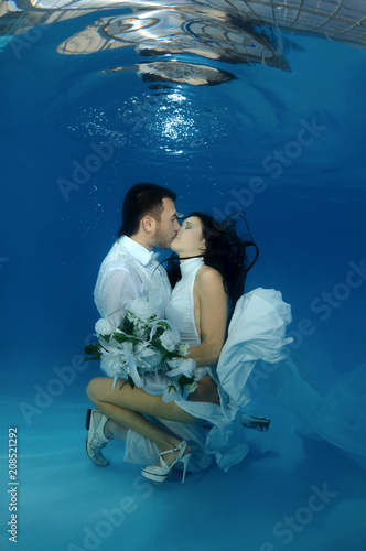 The bride and groom kiss underwater in the pool. Underwater wedding photo