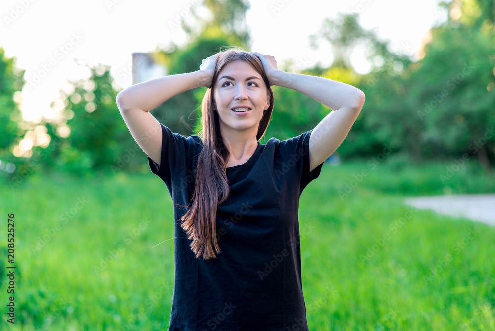 Beautiful brunette girl with long hair. Emotionally rolled her eyes upwards Do not dream of fantasy. Smiles on teeth braces. Summer in nature among green bushes. Beautiful brunette girl with long hair. Emotionally rolled her eyes upwards Do not dream of fantasy. Smiles on teeth braces. Summer in nature among green bushes.