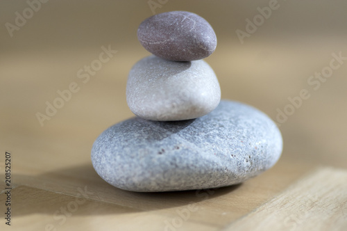 Group of zen stones pile, grey meditation pebbles tower on light brown wooden background in sunlight