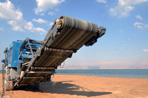 Quarry harvester unit with heavy equipment. Construction industry. building a road and hotel on the Dead Sea, Israel. horizontal blue sky and white clouds background.