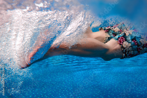 Men's legs swimming underwater in the swimming pool in summer photo