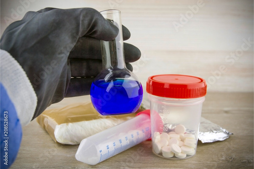 the laboratory assistant of the customs laboratory shows a flask with a positive test result for opiate content in samples, a short focus, vignetting