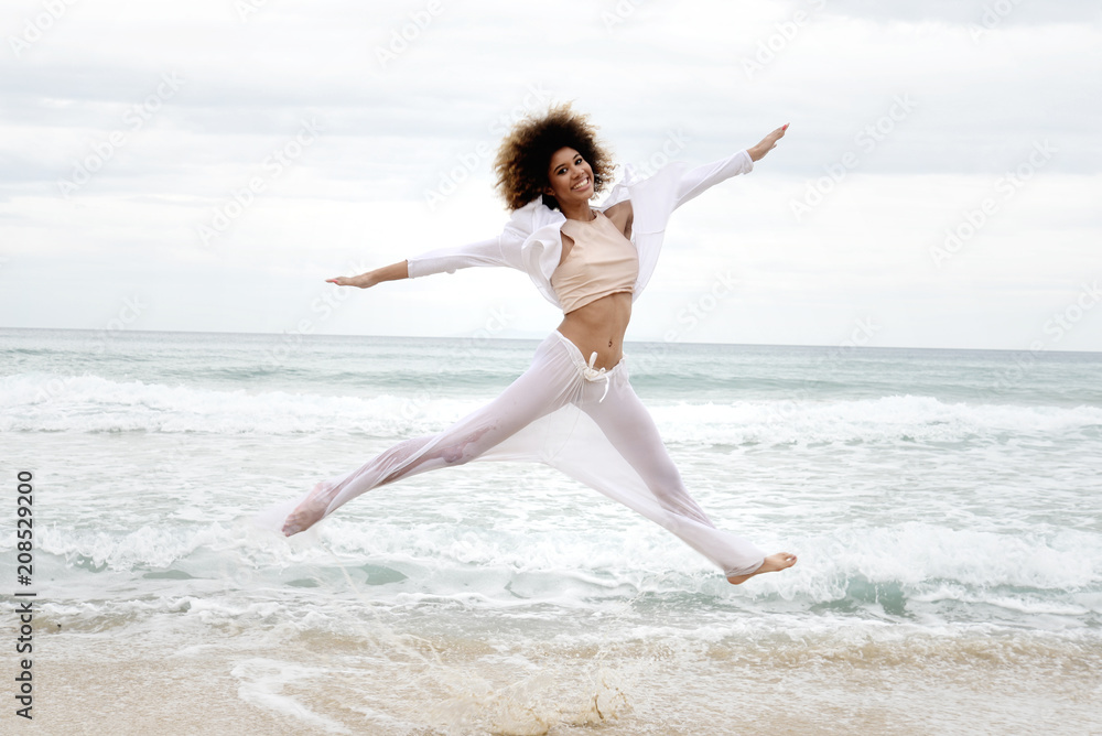 beautiful girl with afro hair and white dress jump on the beach beautiful girl with afro hair and white dress jump on the beach