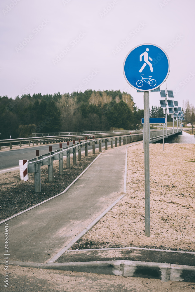 Blue road sign of bike and foot path in Belarus. Sign mounted on the bridge.