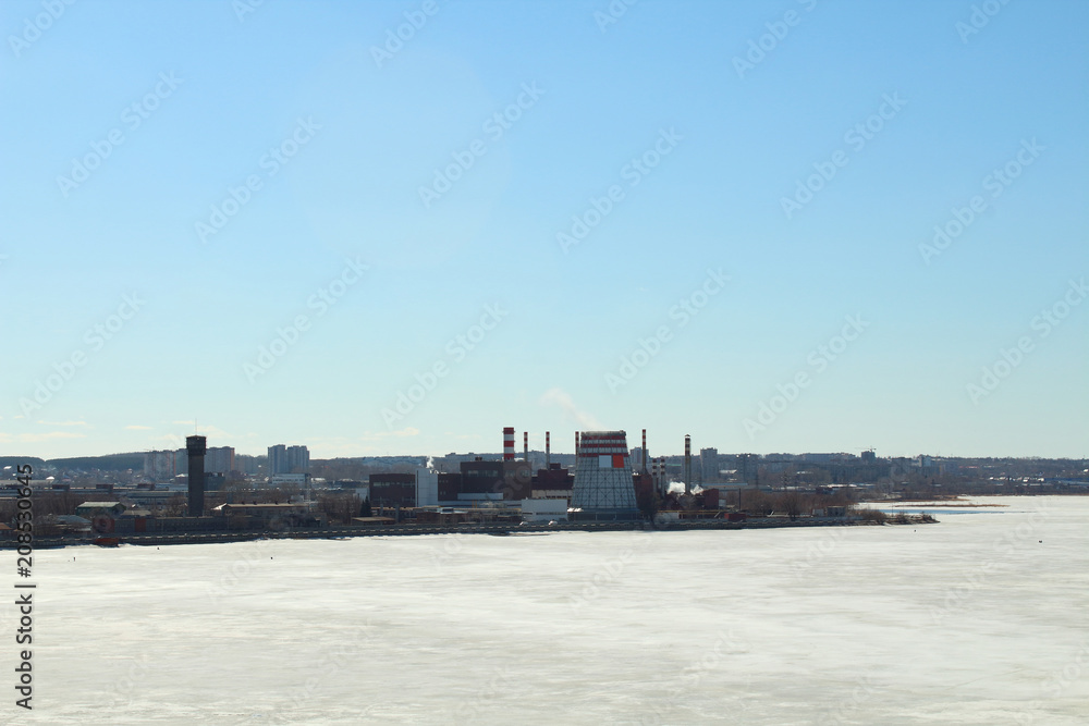 Cogeneration plant on the bank of a city pond. City landscape. Russia, April, 2018.