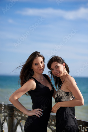 two young woman in a black dresses near the sea © Sergey