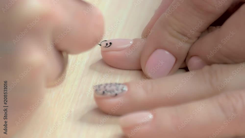 Close up process painting on nails. Manicure master making lace draw on female nails in beauty salon. Nail salon service and business. Close up process painting on nails. Manicure master making lace draw on female nails in beauty salon. Nail salon service and business.