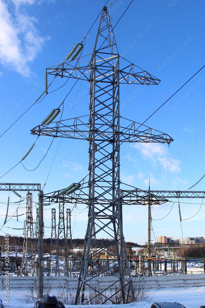 Electricity transmission - Steel support (electricity pylon) of high-voltage overhead power line in winter against the background of transformers Electricity transmission - Steel support (electricity pylon) of high-voltage overhead power line in winter against the background of transformers