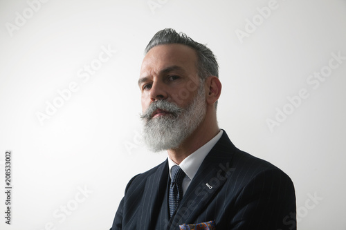 Portrait of confident bearded middle aged gentleman wearing trendy suit over empty white background. Studio shot. Horizontal. photo