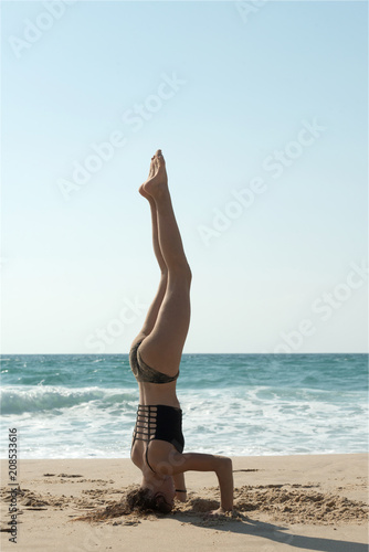 Young girl practicing yoga on the beach