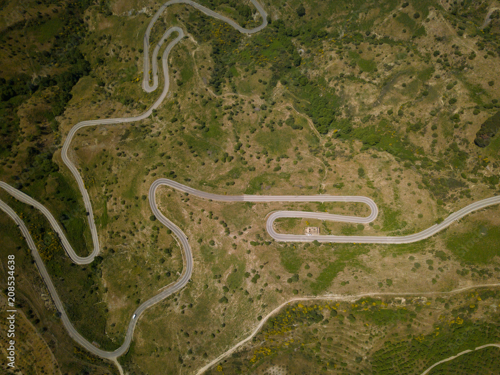 Aerial view of a mountain route with curves near to Etna volcano, Sicily, Italy. Ruined building and car.