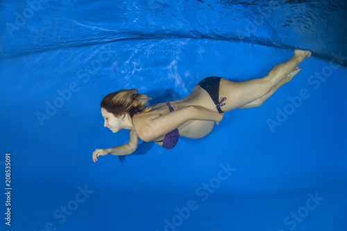 Young pregnant woman in a bikini under water in the pool
