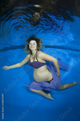 Young pregnant woman in a bikini under water in the pool