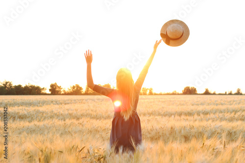 girl in a field on a sunset background throws a hat in the sky. photo