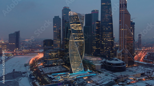 Photography Late evening aerial shot of Moscow-city business towers with illuminated windows and Bagration bridge over the frozen river Moskva
