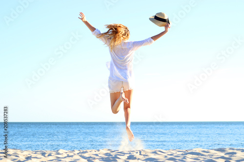 the girl is jumping against the sea.