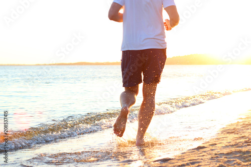 the guy runs along the seashore against the sunset © White bear studio 