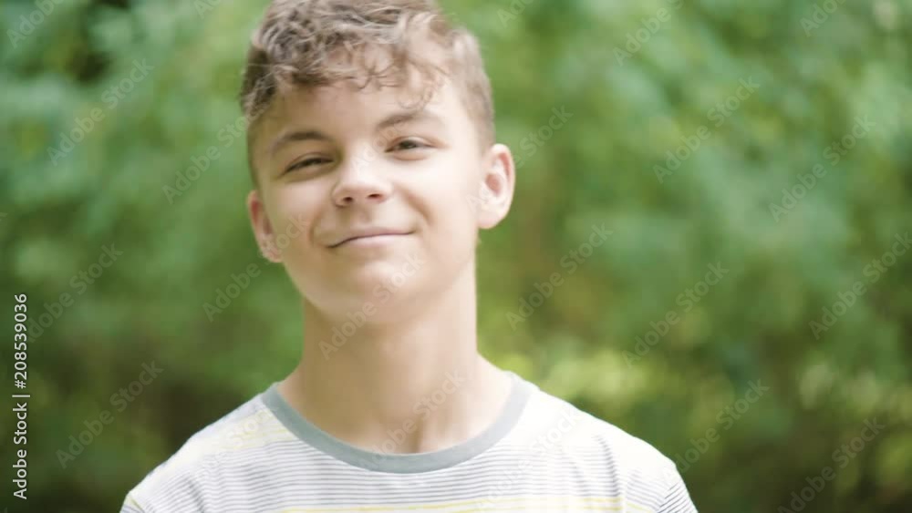 Close up emotional portrait of caucasian smiling teen boy. Handsome guy. Funny cute teenager in summer park at day. Child looking at camera. Close up emotional portrait of caucasian smiling teen boy. Handsome guy. Funny cute teenager in summer park at day. Child looking at camera.