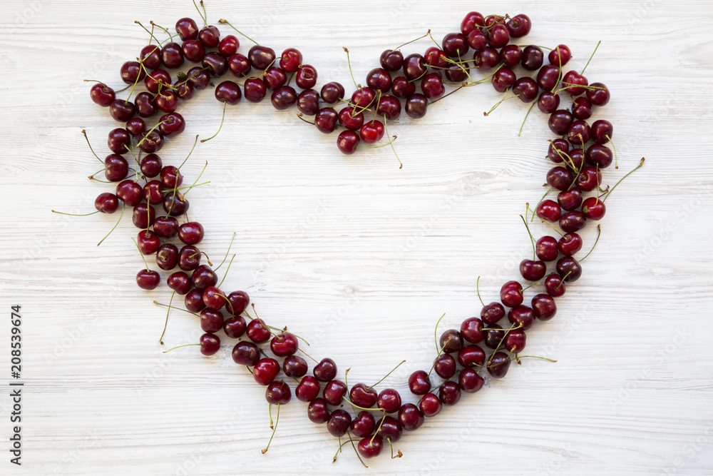 Cherries in the shape of heart on white wooden background, top view. Cherries in the shape of heart on white wooden background, top view.