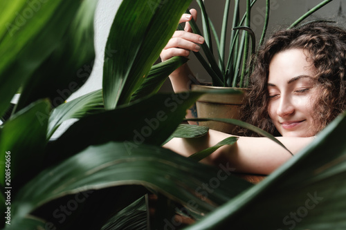 beautiful young brunette girl with a green plant in pot