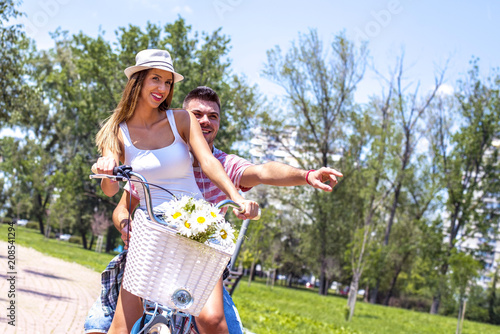 Lovely couple riding a bike with the basket in the park