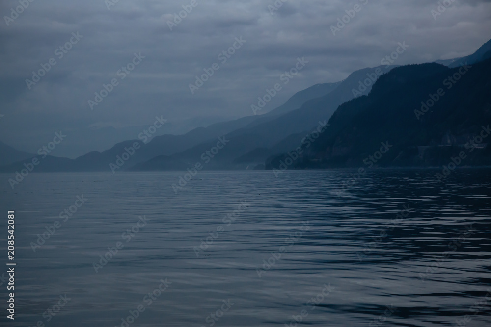 Beautiful background view of the Canadian Mountain Landscape during a dark and moody evening. Taken in Howe Sound, North of Vancouver, British Columbia, Canada.