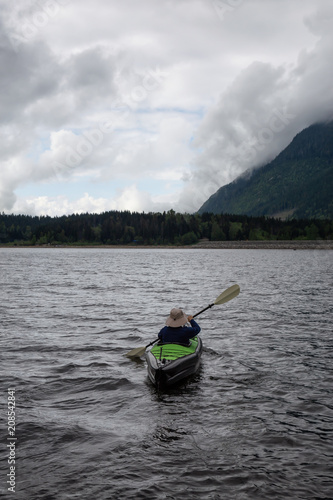 Adventurous Man on a Kayak is enjoying the beautiful Canadian Mountain Landscape. Taken in Jones Lake, near Chilliwack and Hope, East of Vancouver, BC, Canada.