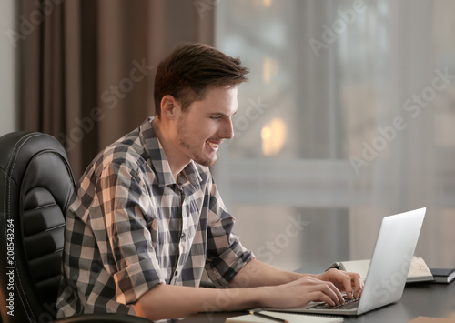Young man working with laptop indoors