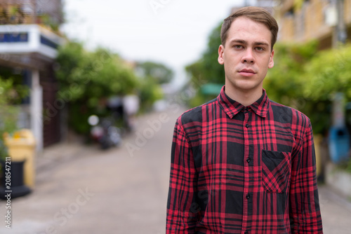Young handsome man wearing red checkered shirt in the streets ou