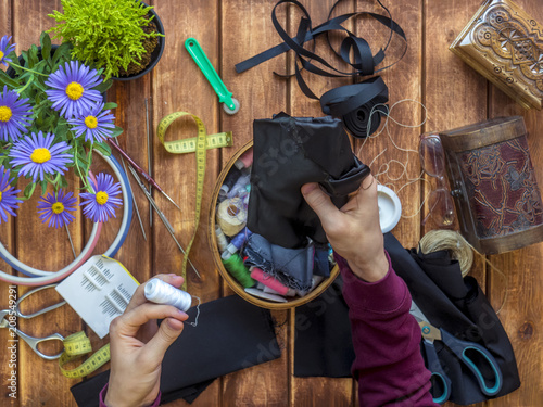 person holding thread roll and cloth flat lay on table