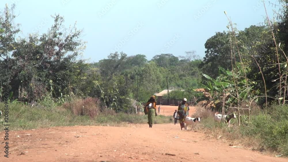 Women walking down a dirt road in remote African village Women walking down a dirt road in remote African village
