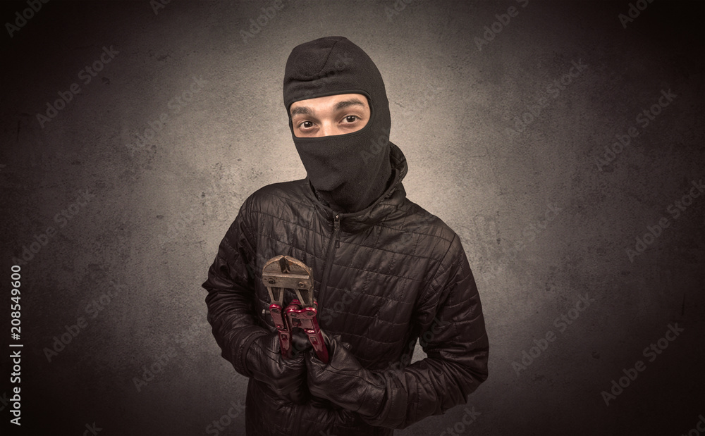 Burglar standing in black clothes and balaclava on his head.