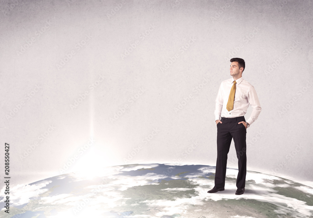 A young elegant office worker standing on top of a drawn world globe while celebrating his successful career concept. A young elegant office worker standing on top of a drawn world globe while celebrating his successful career concept.