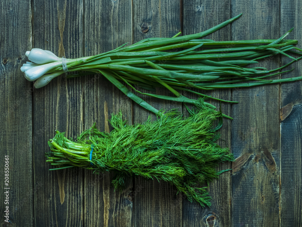bunch of green onion and dill on a wooden surface bunch of green onion and dill on a wooden surface