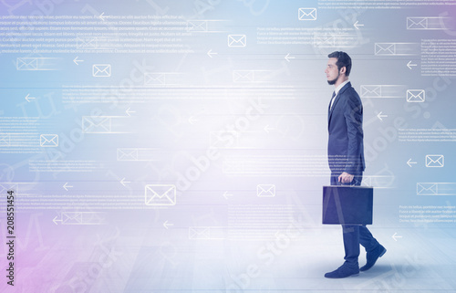 Handsome businessman walking in suit with briefcase on his hand and online communication concept around  