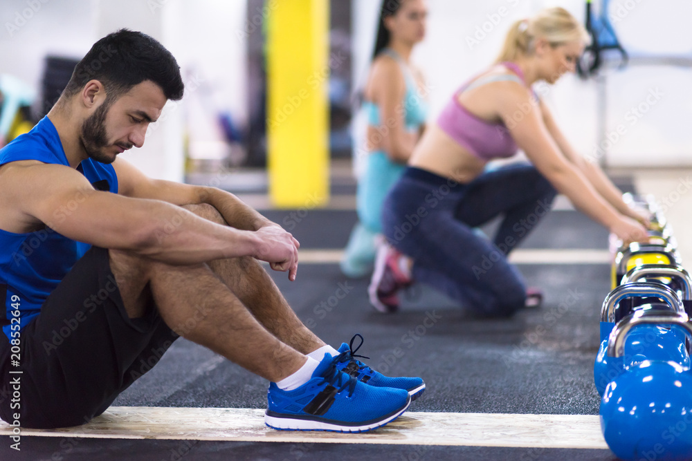 Naklejka premium young athletes doing pushups with kettlebells