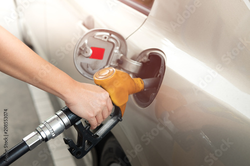 Closeup of man pumping gasoline fuel in car at gas station. Fuel nozzle with hose in hand © feelartfeelant