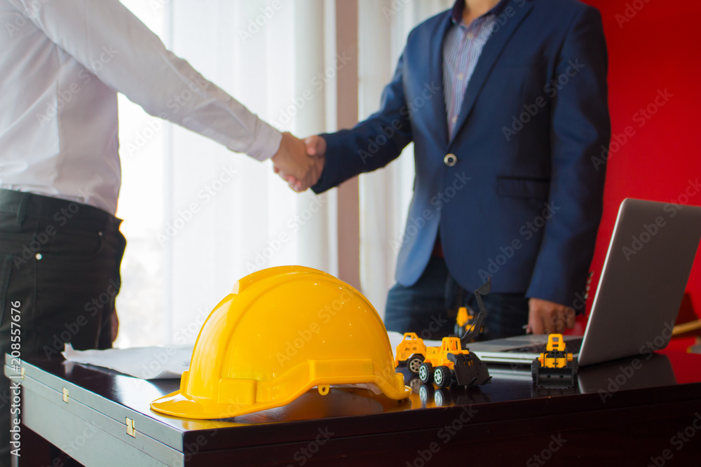 Asian engineer shaking hands with the business customer , finishing up a meeting , focus on yellow helmet Asian engineer shaking hands with the business customer , finishing up a meeting , focus on yellow helmet