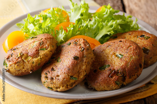 Delicious burgers of tuna with spices are served with fresh vegetable salad close-up on a plate. horizontal