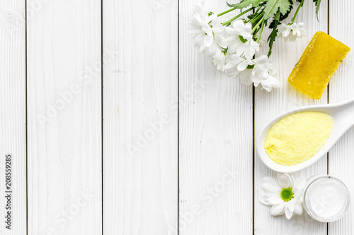 Natural organic spa cosmetics for skin care with chamomile. Spa salt, cream, soap on white wooden background top view copy space