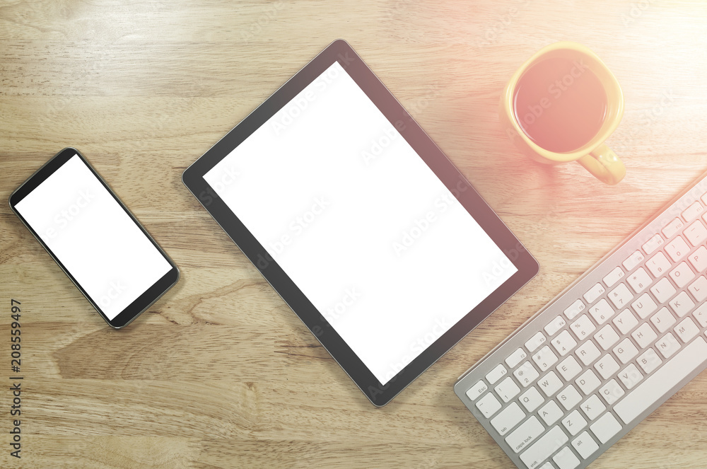 blank screen smartphones and tablet PC on the wooden desktop with computer keyboard and a cup of coffee in composition with copy space for your text blank screen smartphones and tablet PC on the wooden desktop with computer keyboard and a cup of coffee in composition with copy space for your text