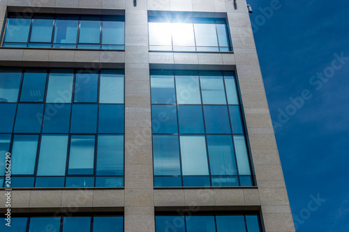 Modern office building in minimalism style with reflection of sunlight and against a blue sky background