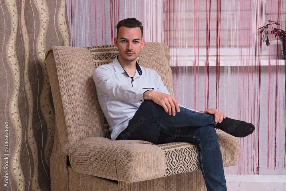 Portrait of a handsome young man sitting on the sofa Portrait of a handsome young man sitting on the sofa