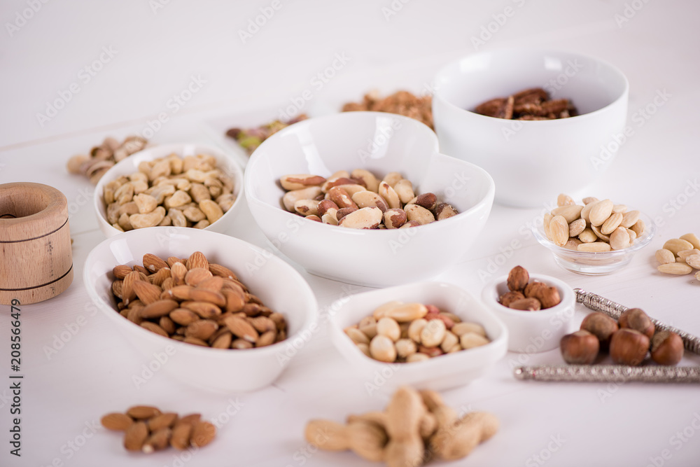 variety, mixture of different nuts on white background in white bowls variety, mixture of different nuts on white background in white bowls