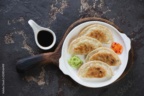 White plate with fried korean potstickers, view from above on a brown stone background, studio shot