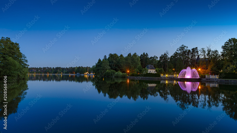 Obraz premium Fountain with illumination on the shore of the evening lake
