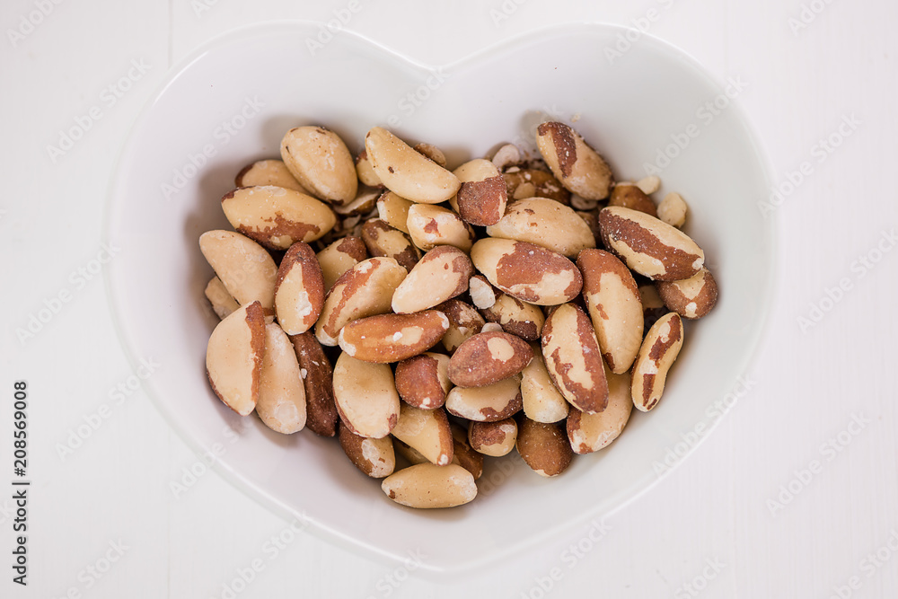 brasil nuts in white heart shape bowl brasil nuts in white heart shape bowl