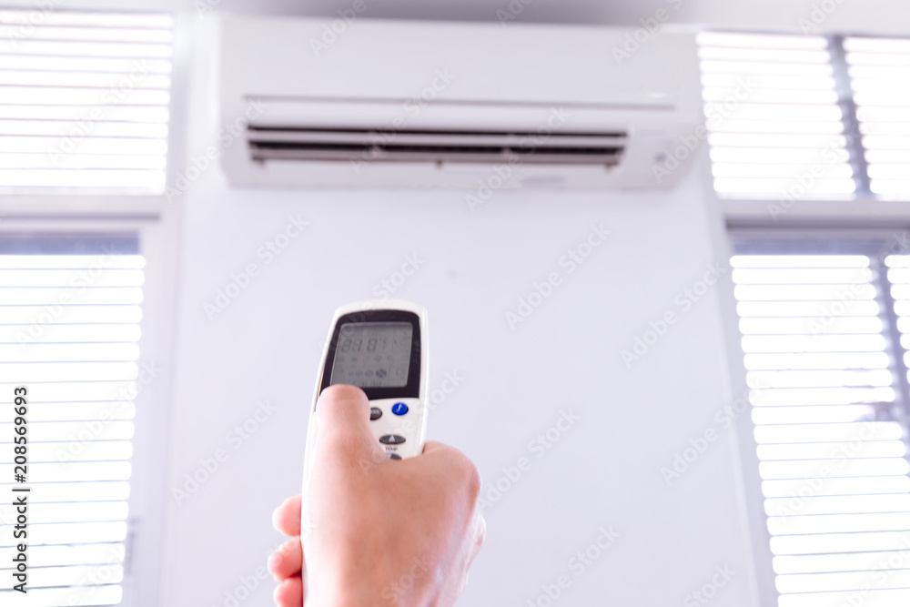 Air conditioner with remote controller,inside the room with man operating remote controller. Air conditioner with remote controller,inside the room with man operating remote controller.