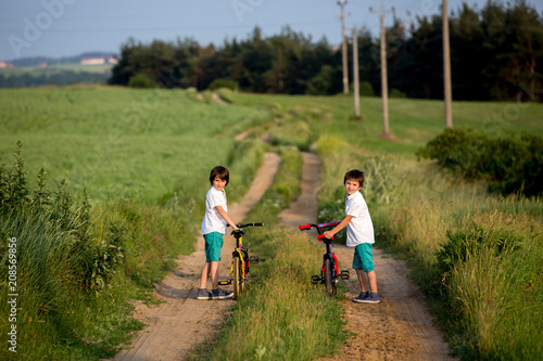 Sporty children, boy brothers, riding bikes on a rural landscape together