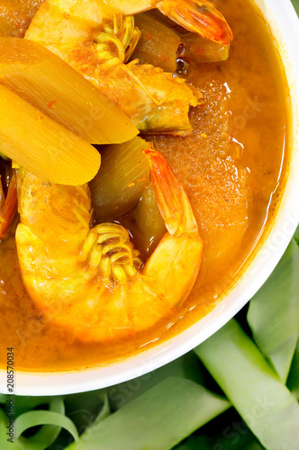 Shrimp in yellow curry with trunk green taro in white bowl on banana leaf, Thai food